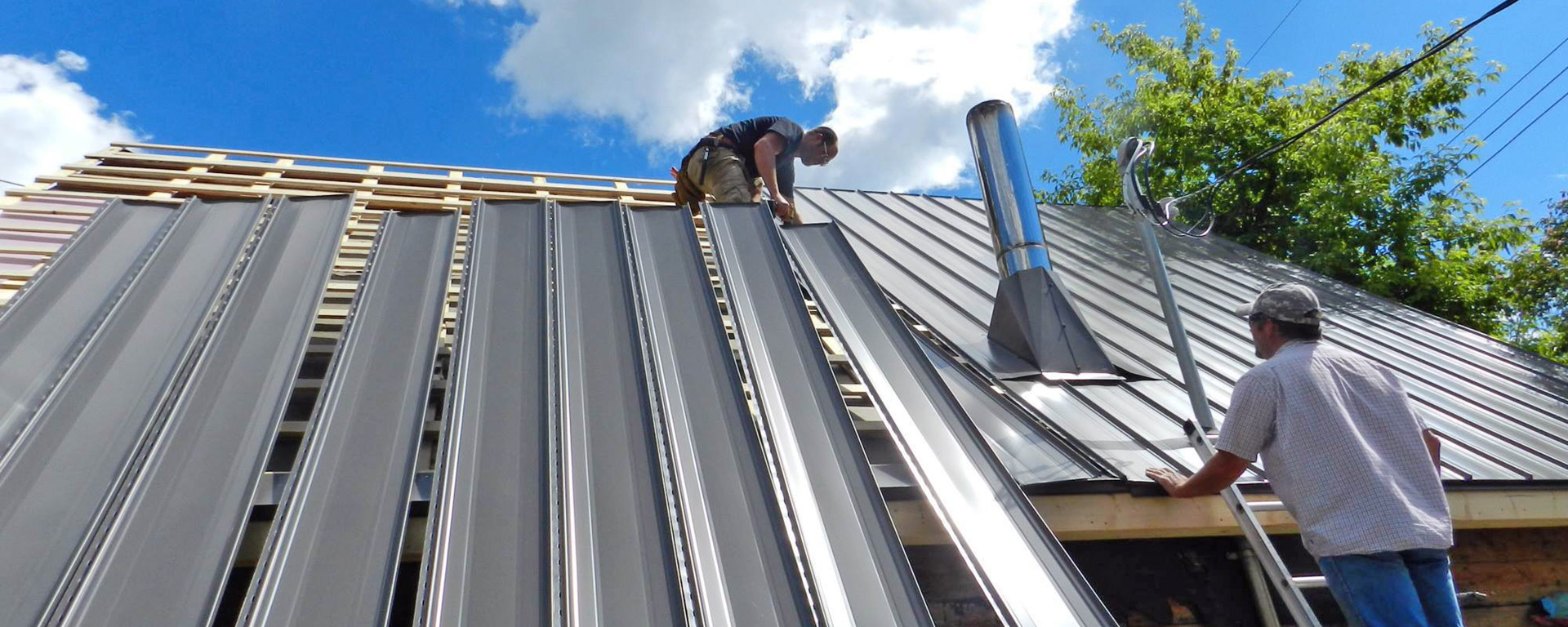 Two men installing metal panels on a roof 