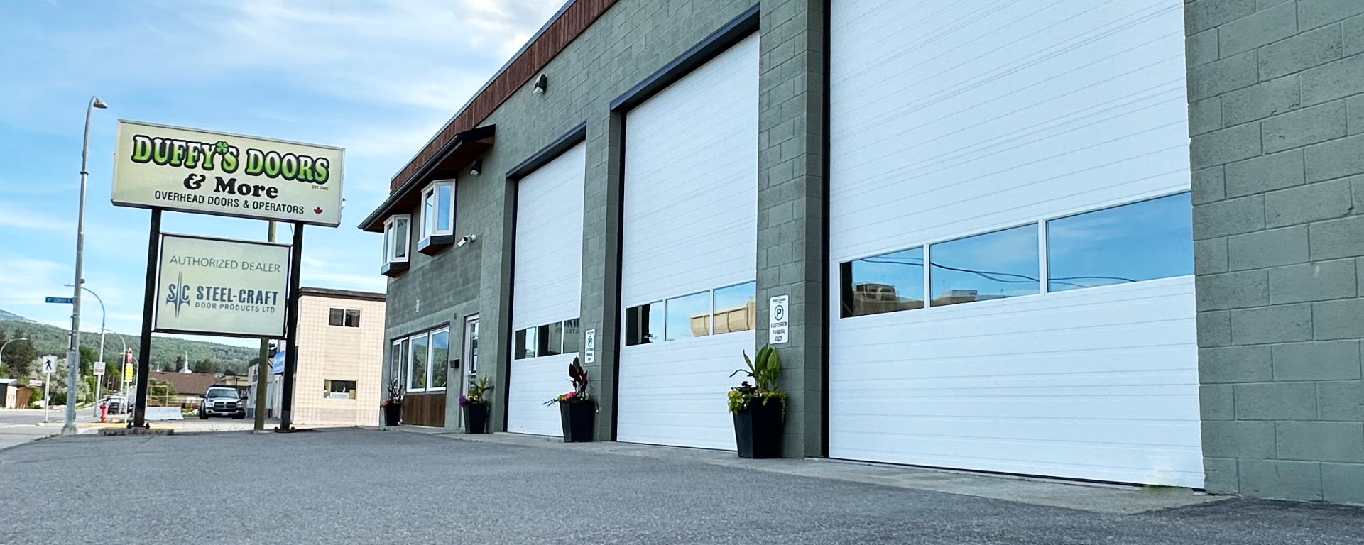 A wide banner image showing the Duffy's Doors & More facility, at 45 7th Ave S, showing several large white commercial bay doors 