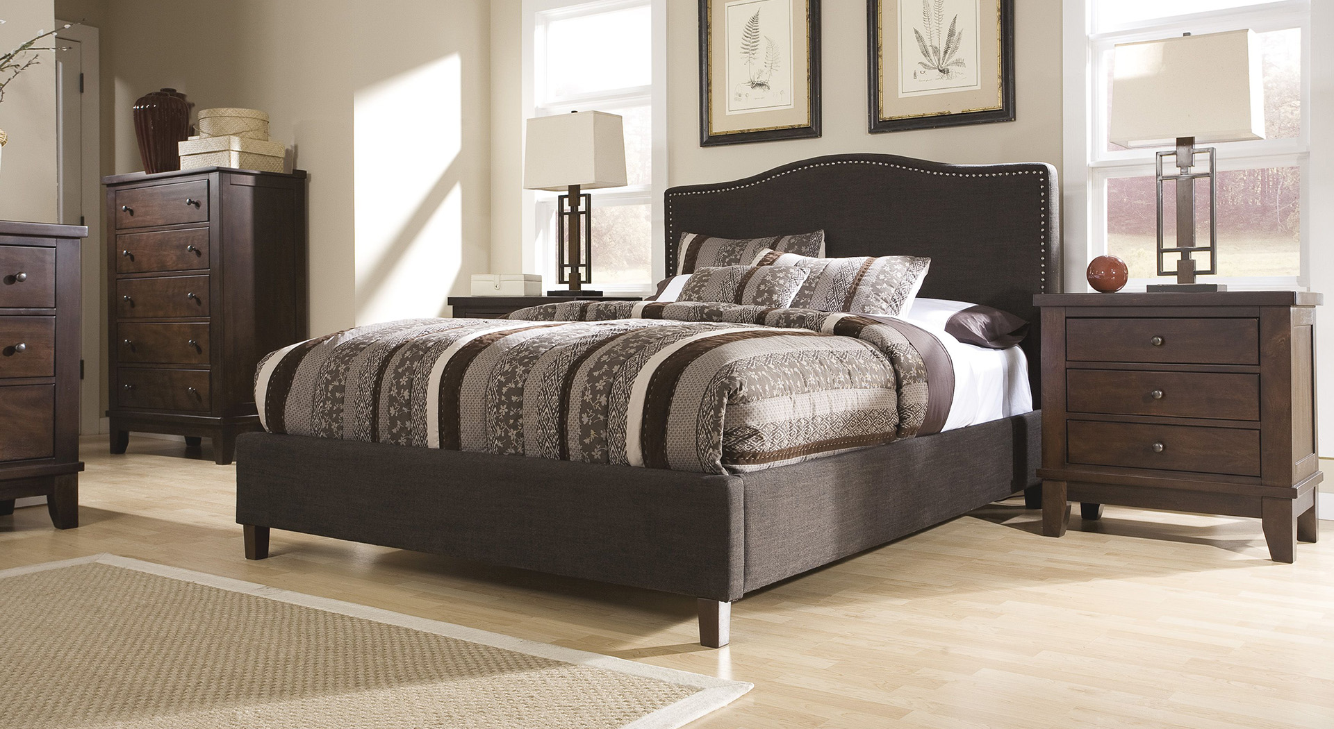 A queen-size bed with grey decor and a striped comforter 