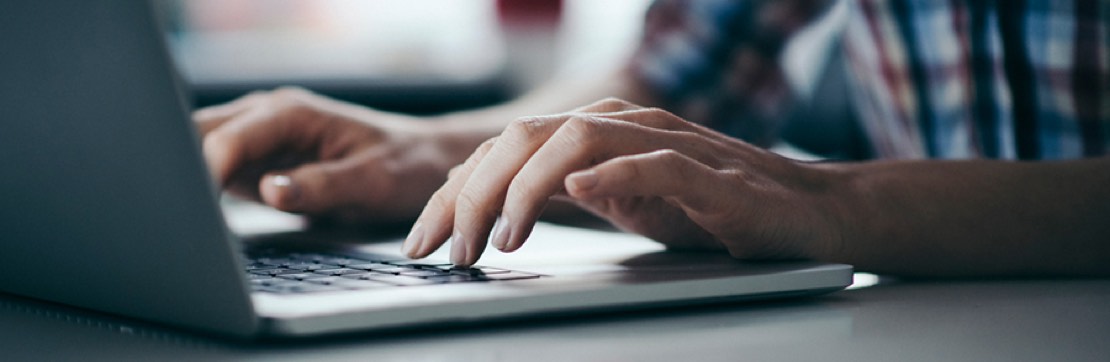 Person’s hands typing on a laptop