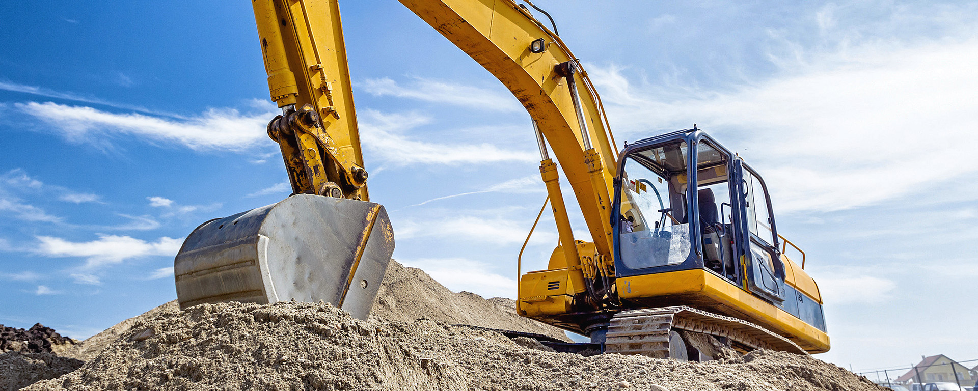 An excavator stopped with its bucket in the sand. 