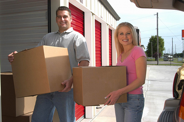 A man and woman each carrying a box outside