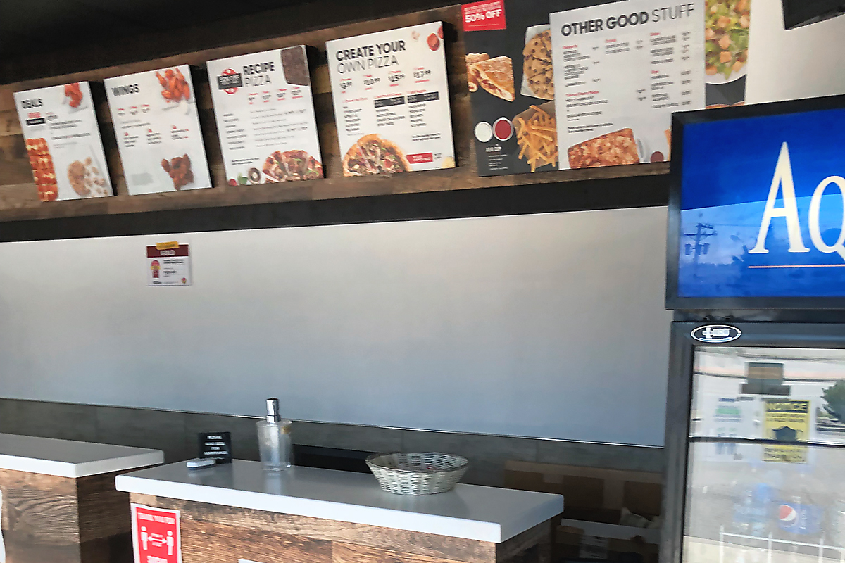 Inside Pizza Hut with menus displayed on the wall 