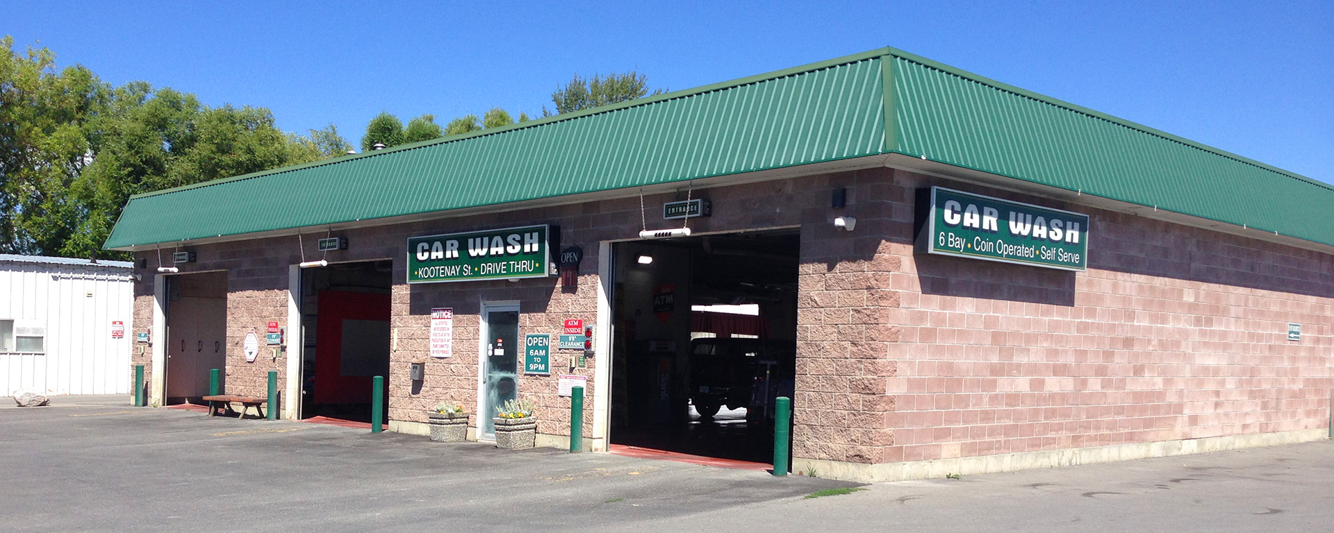 Exterior of Kootenay Street Carwash in Cranbrook, with an open washing bay and a sign out front that says “Car wash” in large white letters. 