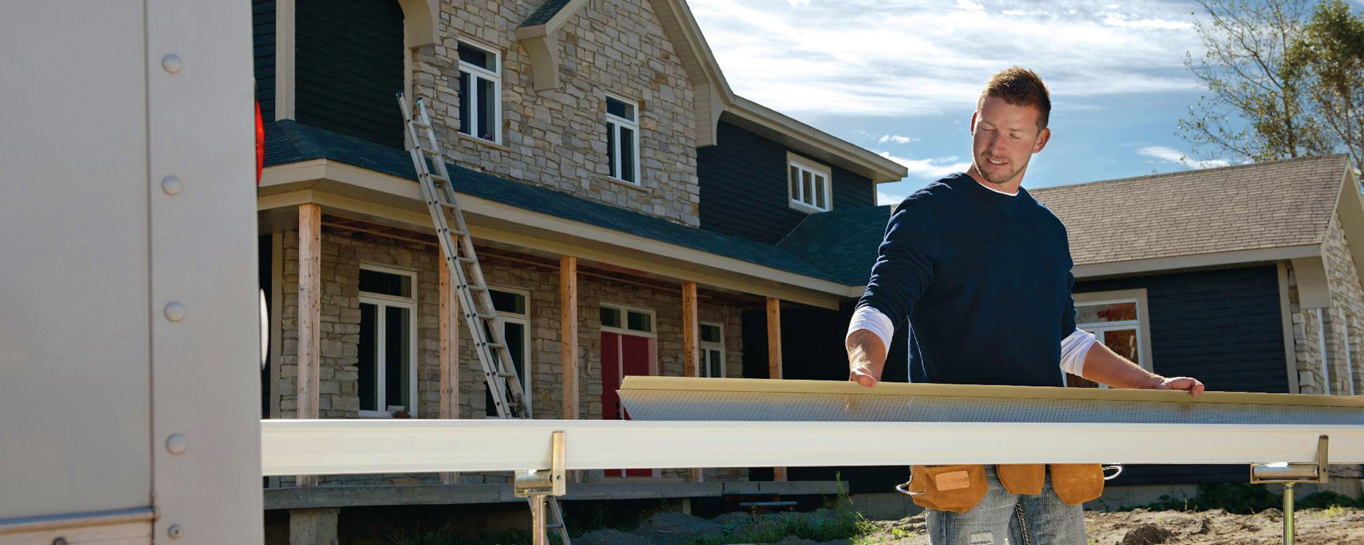 A man building a seamless gutter on a new home site. 