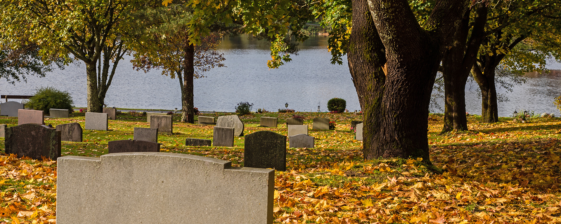 Grave stone in autumn overlooking a pond. 