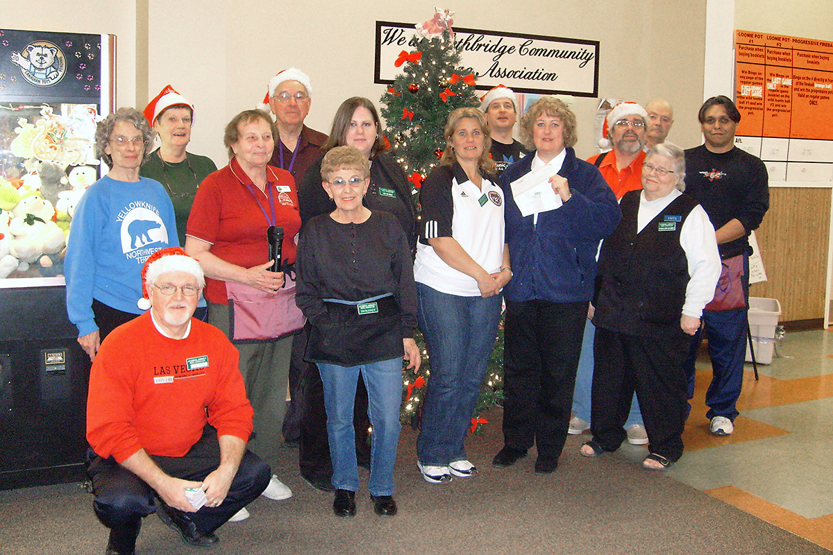Large group of people posing for a staff picture surrounding a Christmas tree