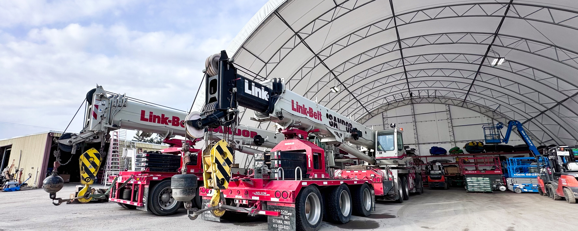 Two large cranes parked under the open shed ad Sandor Rental in Cranbrook, BC 