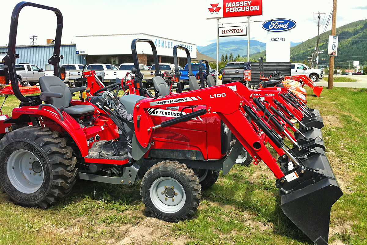 Red tractors parked outside with black shovel attachments 