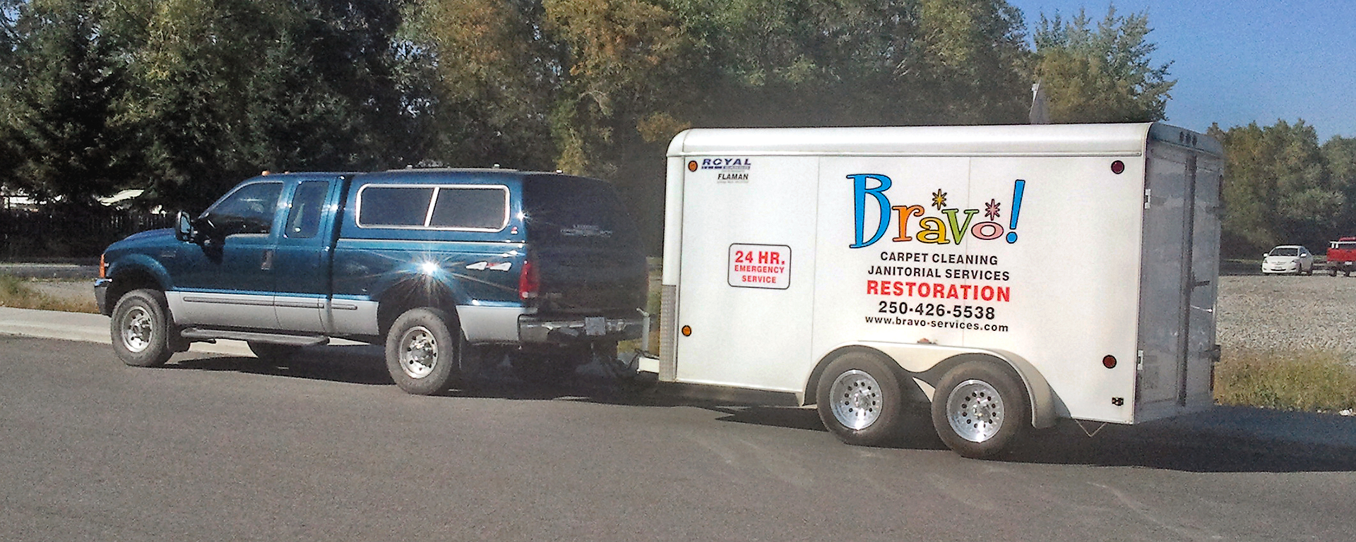 a blue-green truck with a canopy towing a trailer with the Bravo carpet cleaning logo painted on the side 