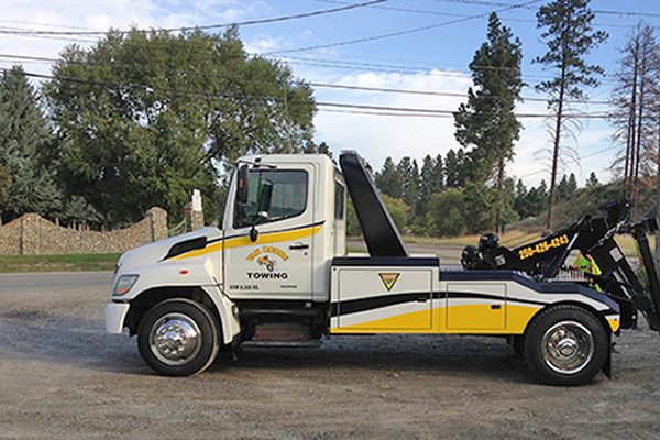 white and yellow tow truck parked outside advertising Van Horne Towing 