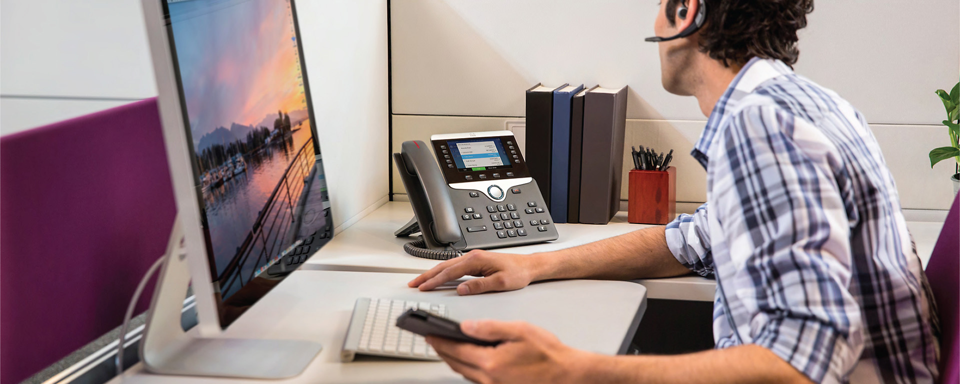 Man taking a call on headset at desk .