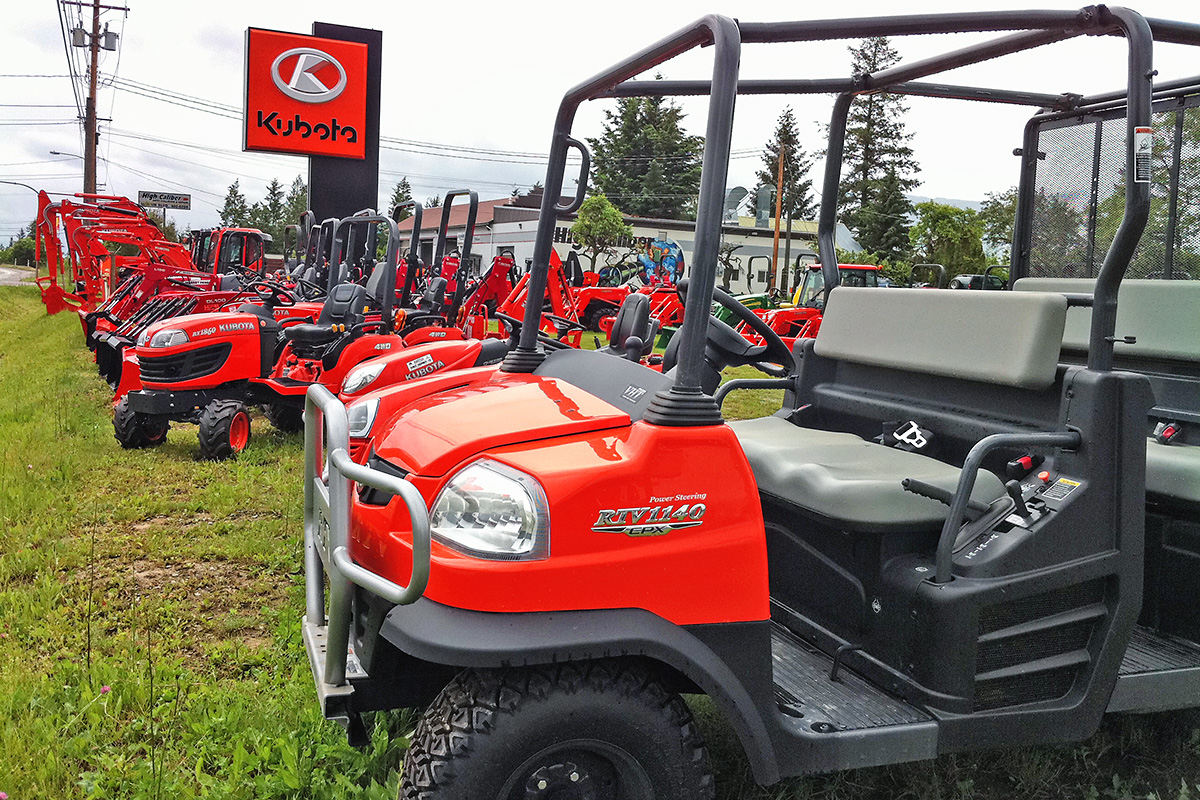 Red ATVs parked outside by an exterior sign advertising Kubota 