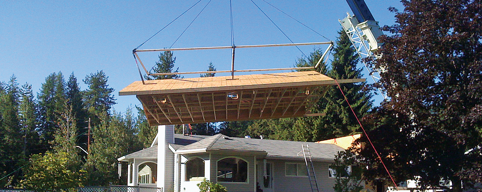 Crane lifting roof onto house addition. 