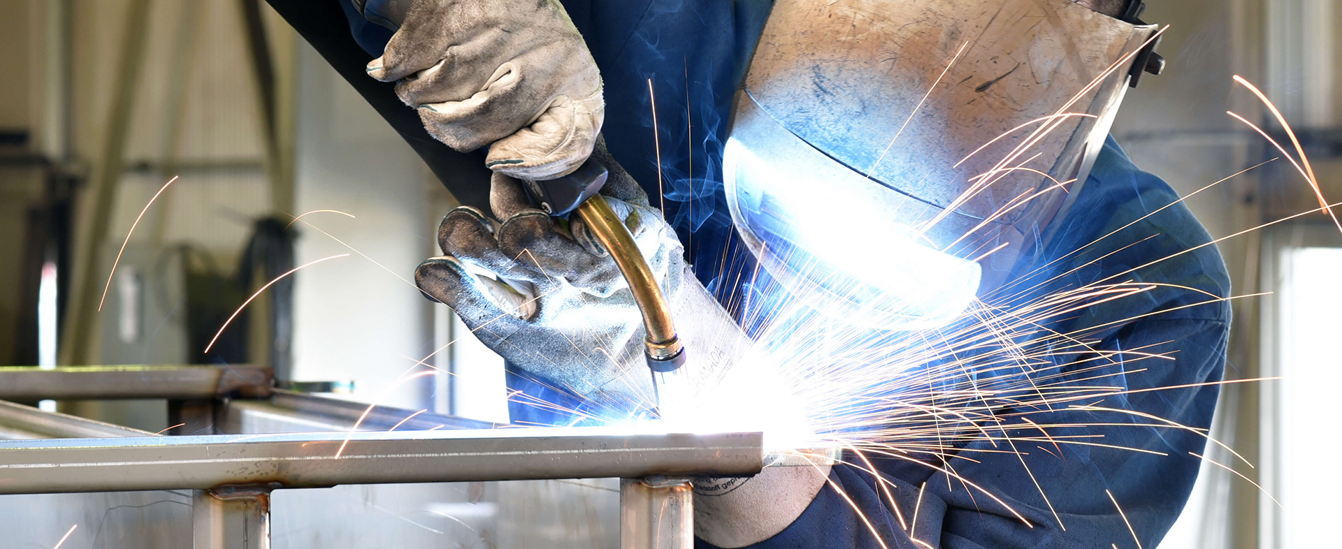 Close-up of a person welding, wearing gloves and other protective equipment 