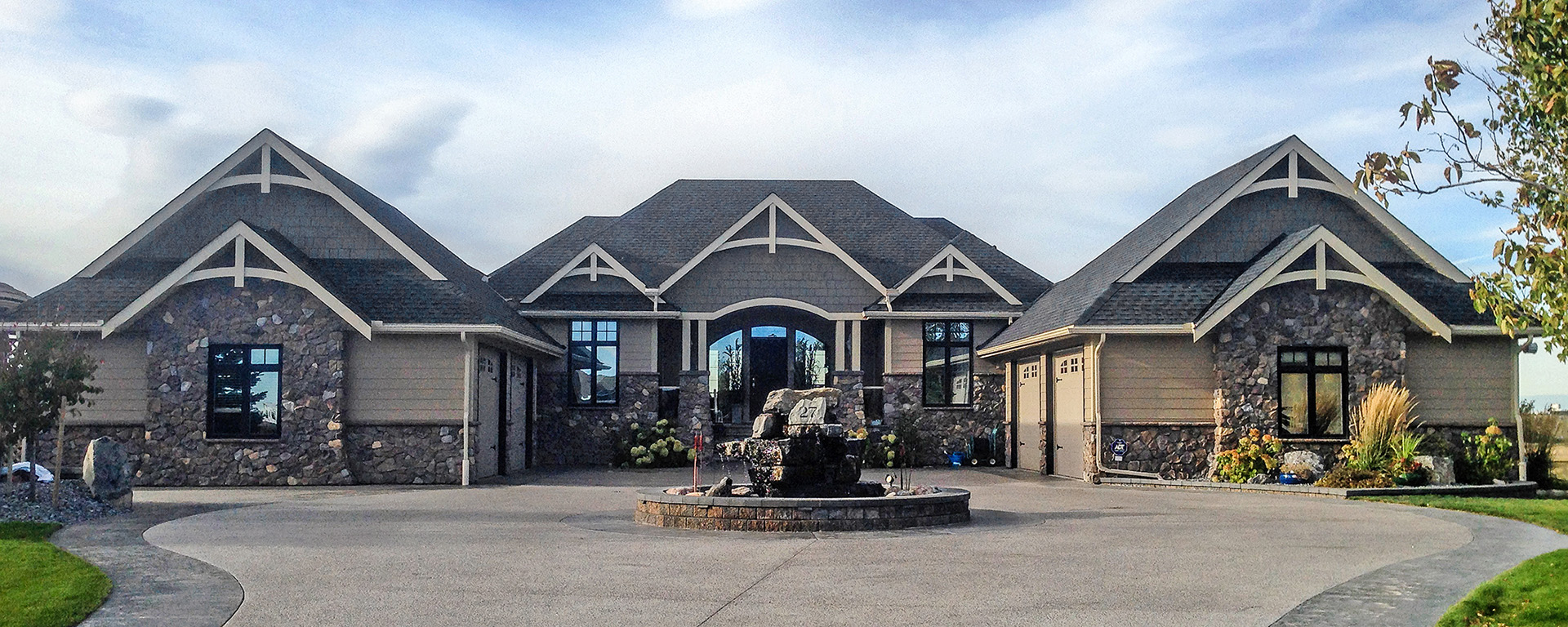 The front of a large home with dark grey shingle roofing 