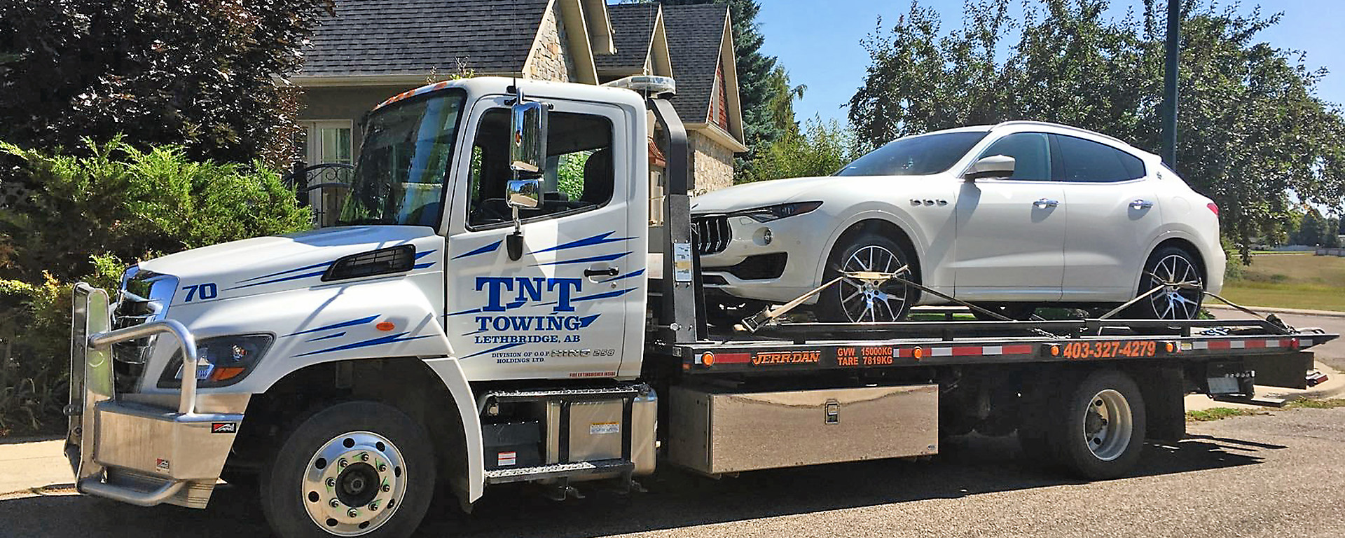 TNT tow truck with flat deck hauling a white 2017 Maserati 