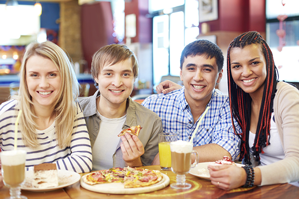 a group of two ladies and two men eating pizza together