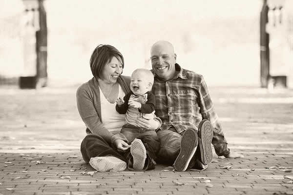 black and white photo of a mom, dad and son sitting outside on the ground 