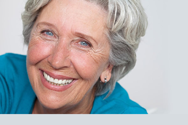 an elderly woman smiling with satisfaction in wearing full dentures