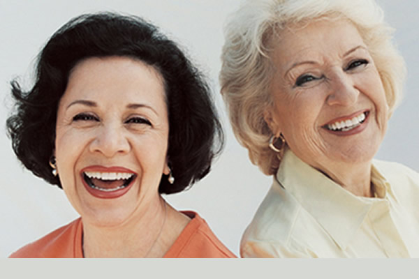 two elderly women smiling with comfort in wearing full dentures