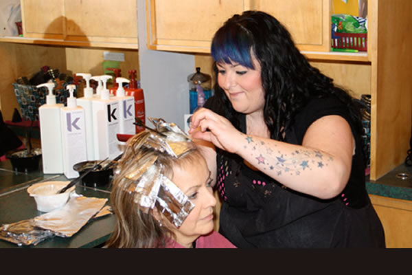 A stylist doing a client's hair at Waves On The Lake Hair Design