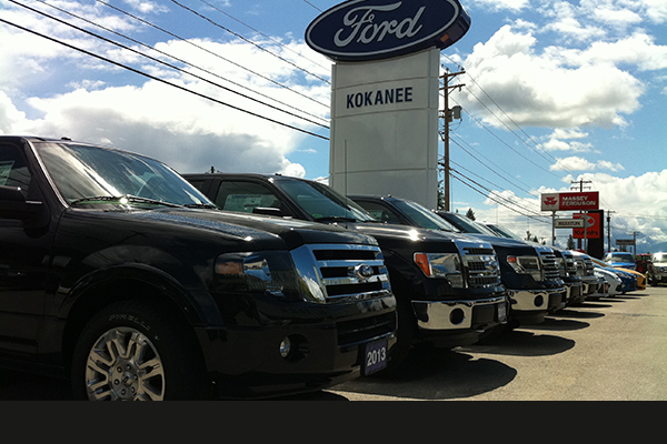 Outside sign Ford in a blue oval mounted on a white pillar in the sales lot