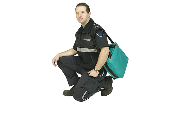 Male dressed in a paramedic uniform carrying a green bag