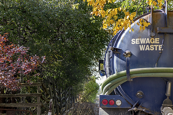 blue sewage waste truck with a holding tank parked outside