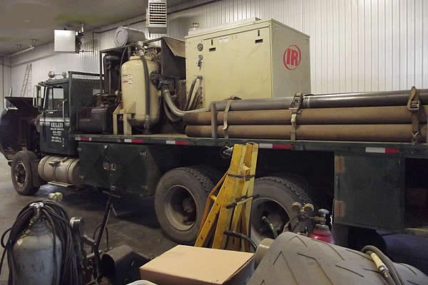 haul truck in the shop with a trailer loaded up with metal piping