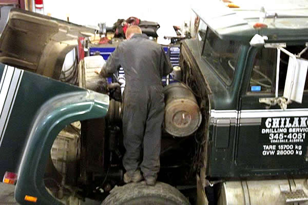 a mechanic suited up to perform engine repairs under the hood
