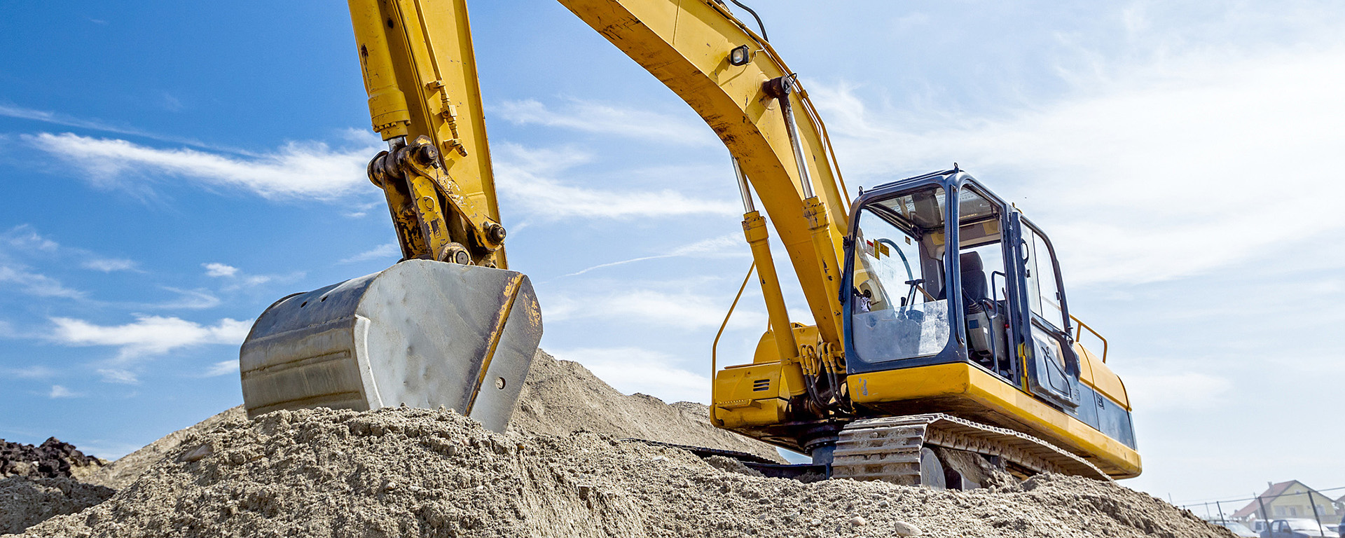 Yellow excavator digging in the dirt with a blue sky in the background 