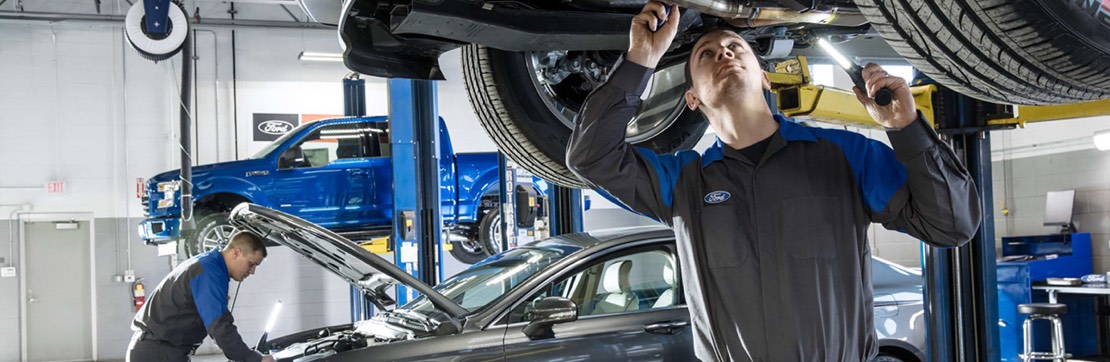 Man leaning forward to work under the hood of a car