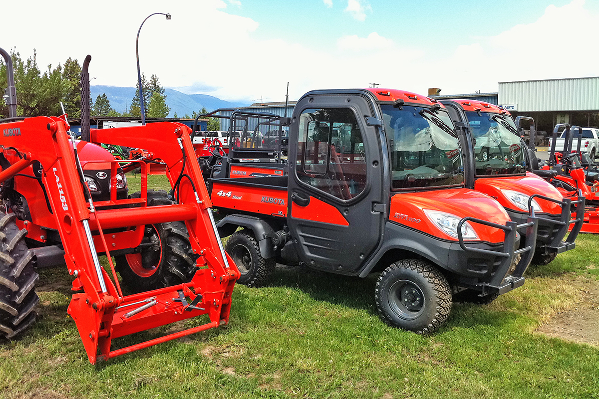 Red tractors and all terrain vehicles parked outside 