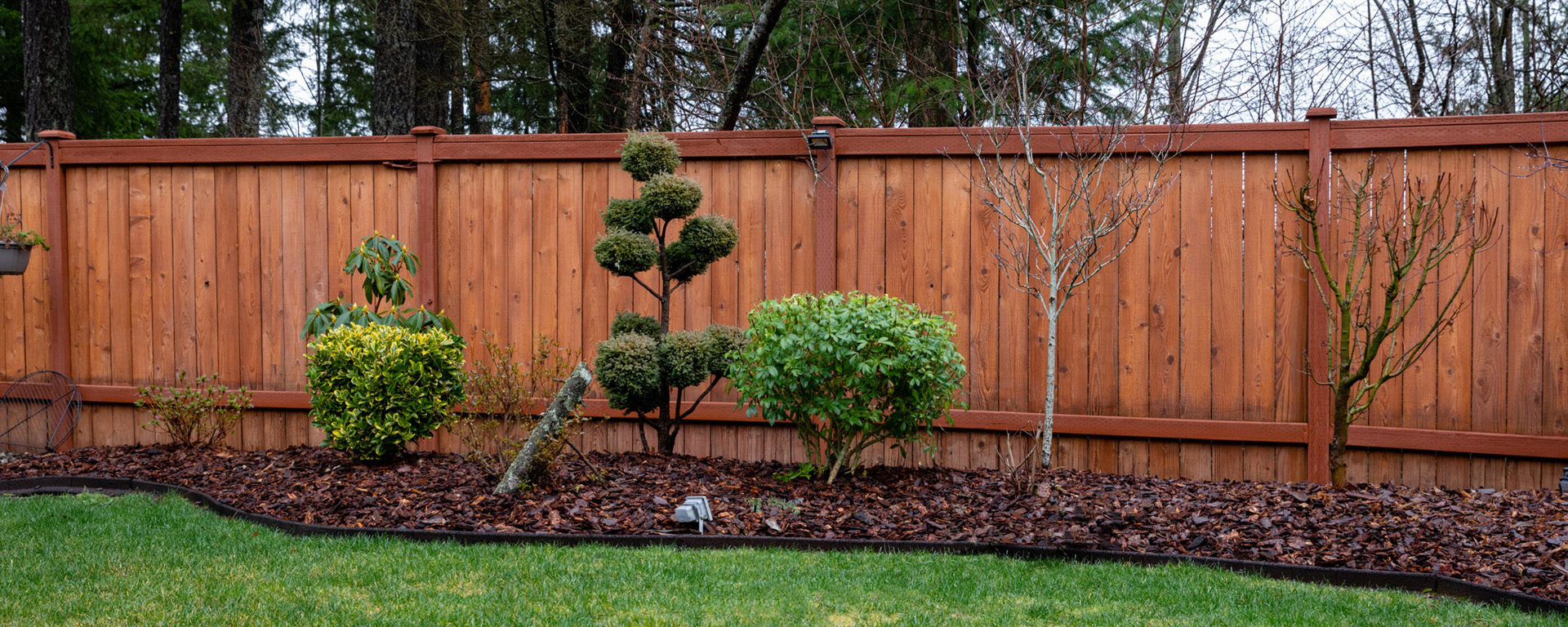 Picture of tall wooden fence and landscaped yard. 