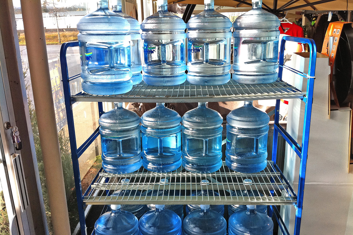 5 gallon blue coloured water jugs on shelves 