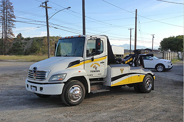 white and yellow tow truck parked outside advertising Van Horne Towing 