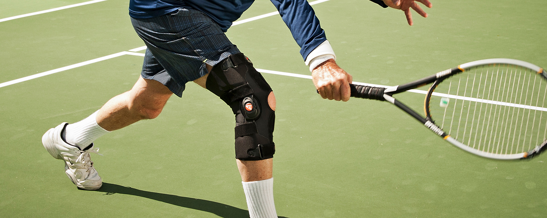 A man playing tennis with a knee brace. 