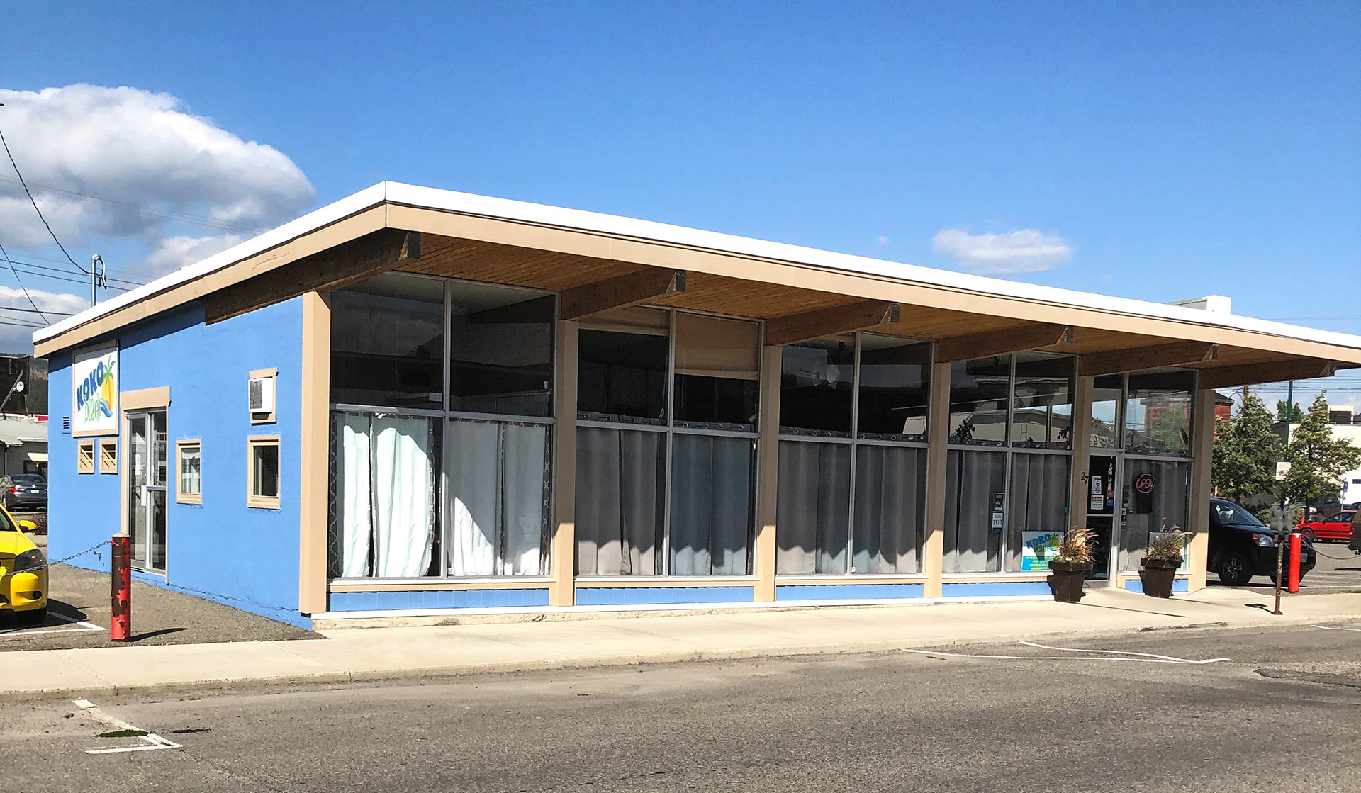 Photo of the Koko Beach Tanning & Hair Salon building. It’s painted a light blue colour with windows across the front of the building. 