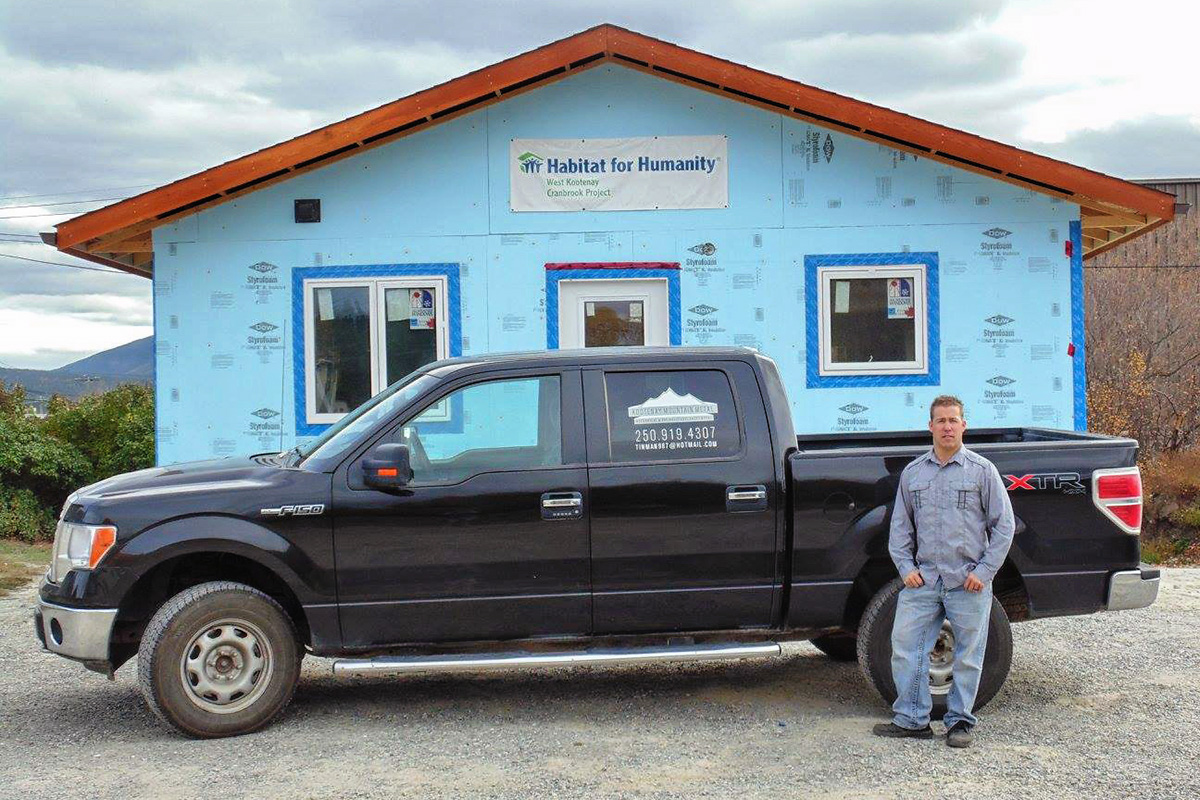 Kevin Johnston, owner of Kootenay Mountain Metal, standing in front of his truck outside of Habitat for Humanity