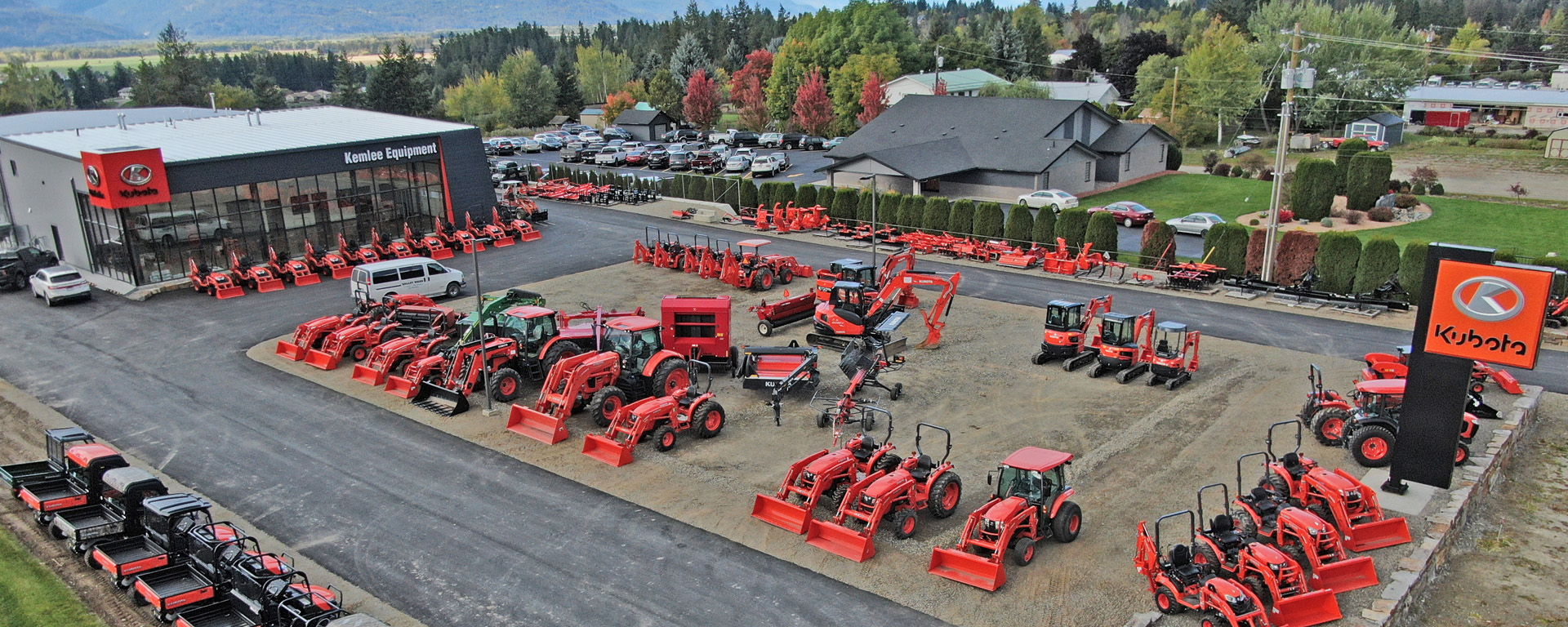 Red tractors parked outside by an exterior sign advertising Kubota 