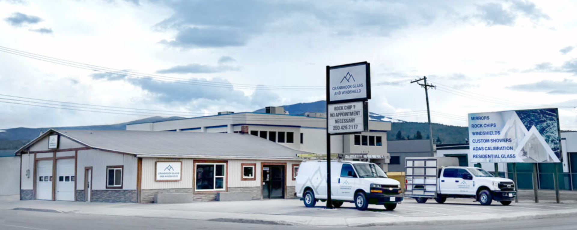 Cranbrook Glass building, with its signage out front, with a bright blue sky and fluffy white clouds above. 