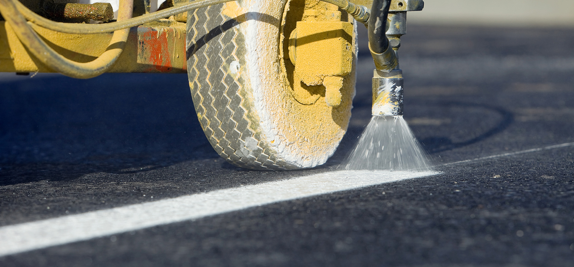 Close-up shot of a truck painting a white line on asphalt 