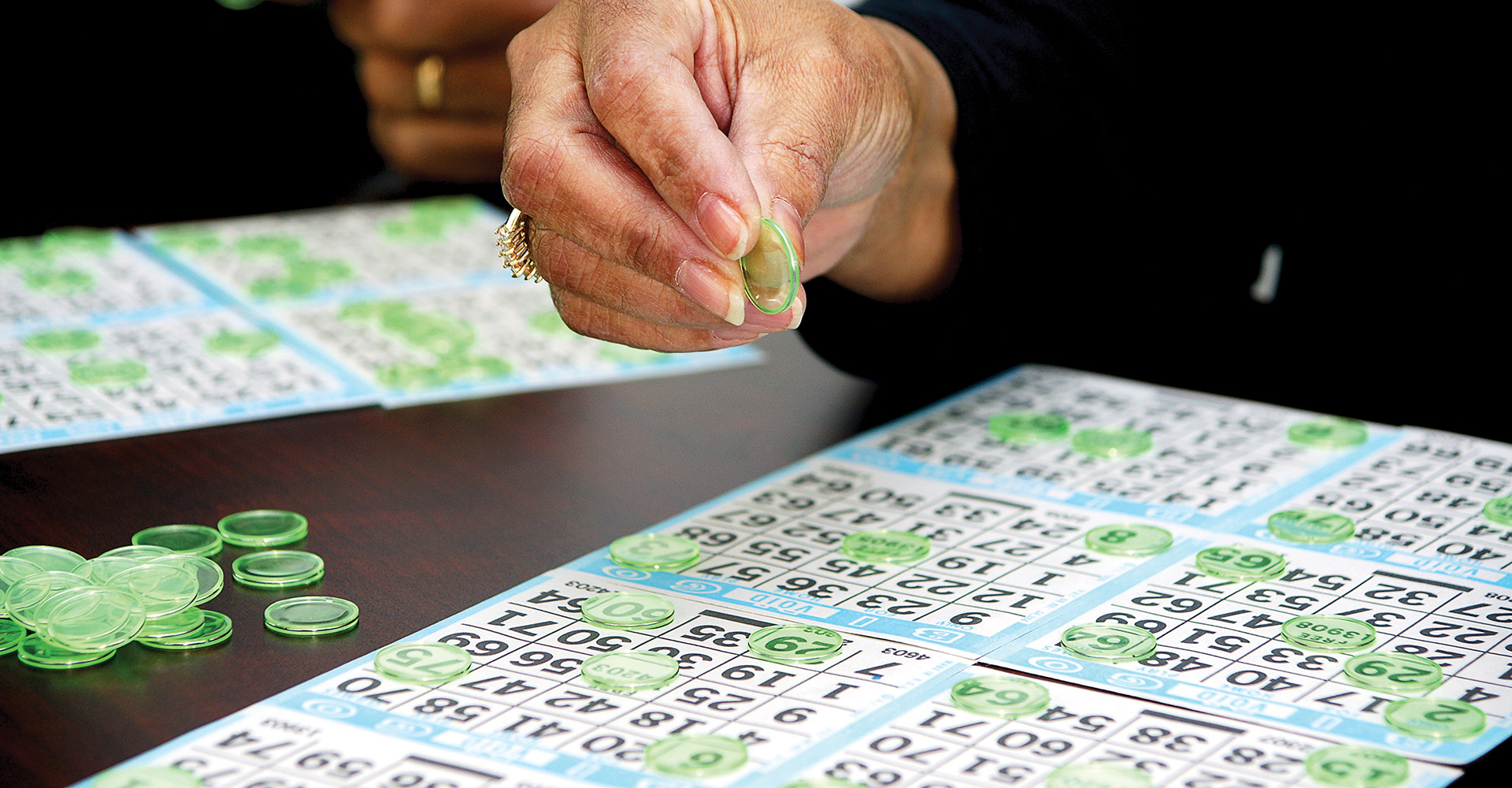 A close up shot of a lady playing bingo using green tokens 
